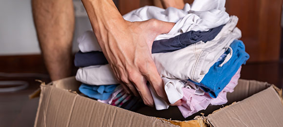 putting clothes in cardboard box to donate